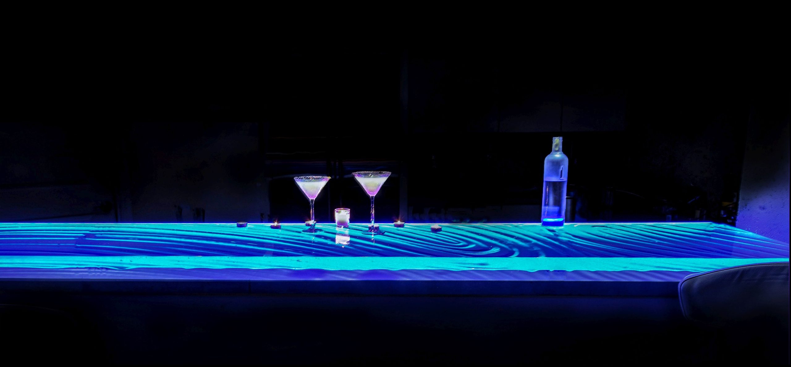 Kiln-formed glass bar top illuminated with blue RGB LED lighting at night, fabricated by Jeff Downing of Downing Designs Tampa Florida