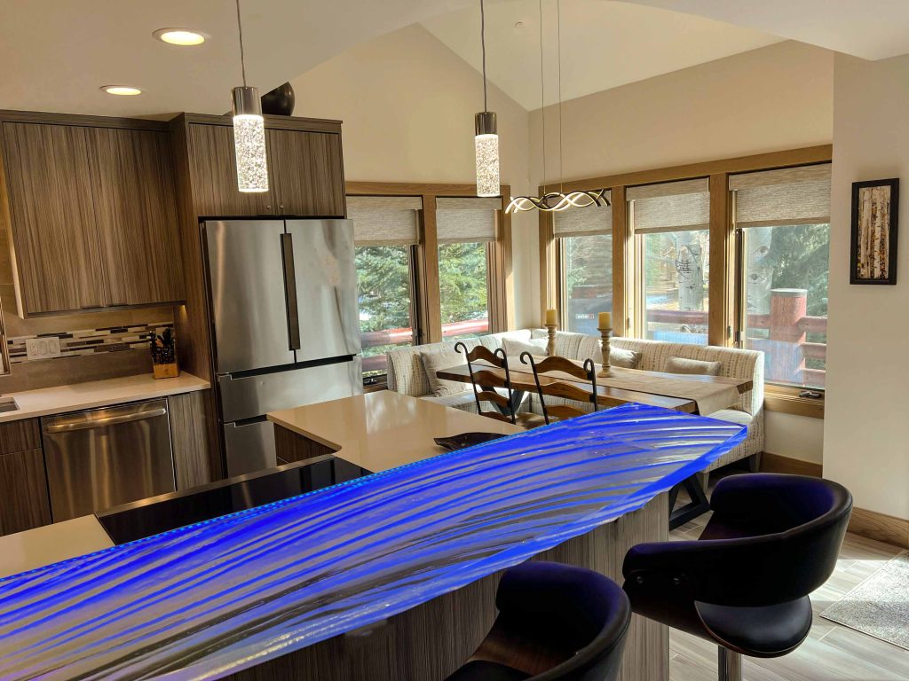 Blue-lit textured glass bar top with mountain views through kitchen windows, Park City Utah