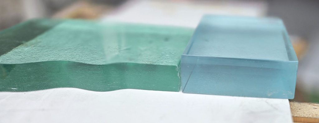 Side-by-side comparison of thick clear fused glass and thick low-iron fused glass, showing the green cast in standard clear glass